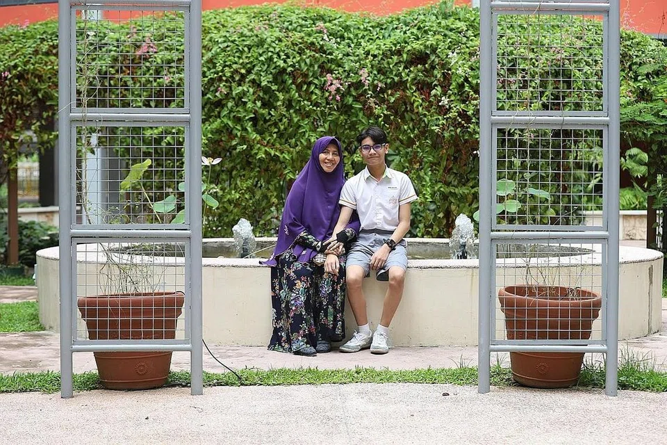 KEHILANGAN IBU TIDAK MENJADI HALANGAN: Pelajar Sekolah Rendaah Palm View, Muhammad Raiyan bersama neneknya, Cik Katirah, selepas mendapat tahu keputusan PSLE. Cik Katirah telah menjadi pengasuh utama Muhammad Raiyan setelah kematian ibunya apabila dia hanya berusia empat tahun. - Foto BH oleh MARCELLIN LOPEZ