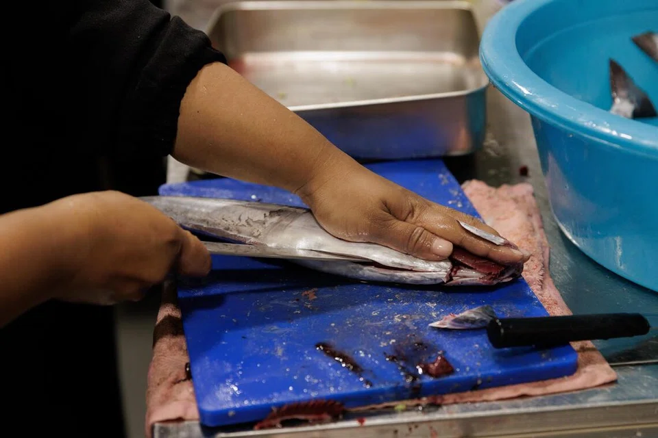 Gerakan tangan Cik Nooraini yang pantas dan cekap menyiang ikan tenggiri untuk hidangan asam pedas di Terumbu. Kemahiran itu diasah sejak beliau membesar di Pulau Semakau.