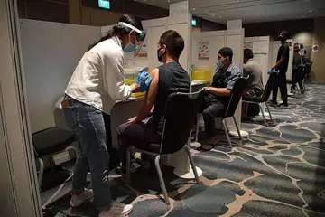 KEADAAN MASIH DINAMIK: Kakitangan hotel menerima vaksinasi Covid-19 di Pusat Konvensyen Raffles City bulan lalu. Dr Janil Puthucheary berkata keadaan Covid-19 di sini dan serata dunia kekal dinamik buat masa ini. - Foto fail BH