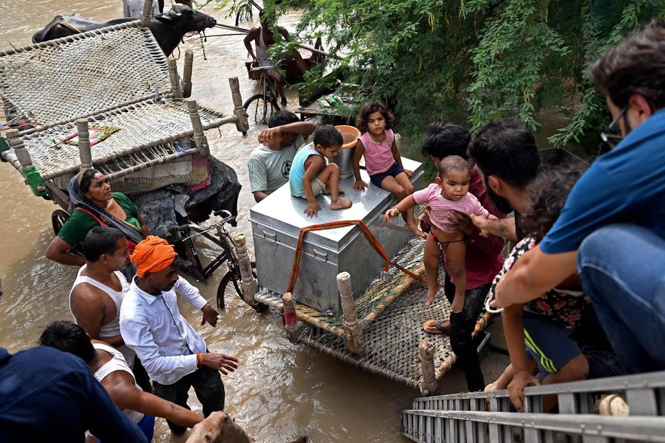 BANJIR MELANDA: Sukarelawan menyelamatkan kanak-kanak dalam kejadian banjir apabila paras air di Sungai Yamuna naik berikutan hujan lebat pada Rabu. 