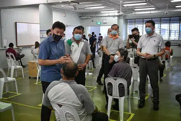 PROGRAM VAKSIN: Encik Chee Hong Tat (kiri) bersama Setiausaha Eksekutif Kesatuan Pekerja Pengangkutan Kebangsaan (NTWU), Encik Melvin Yong (kanan), bercakap bersama pekerja pengangkutan darat yang hadir di pusat vaksin Covid-19 di tapak bekas Sekolah Menengah Hong Kah di Jurong untuk mendapatkan vaksinasi. - Foto BH oleh ARIFFIN JAMAR