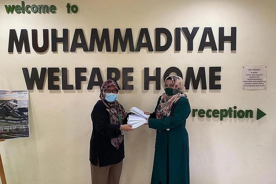 SEBAR KECERIAAN: Pengerusi Dewi@SMCCI, Cik Fadilah Majid (kanan) memberi duit Raya kepada Cik Rubiah, yang akan diagihkan kepada penghuni RKM. - Foto DEWI@SMCCI