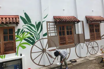 WAJAH BARU: Pelukis mural, Encik Dennis Tan, melukis di permukaan dinding bangunan yang pernah menempatkan Pondok Gelam di 64 Club Street. - Foto BORHAN SAINI