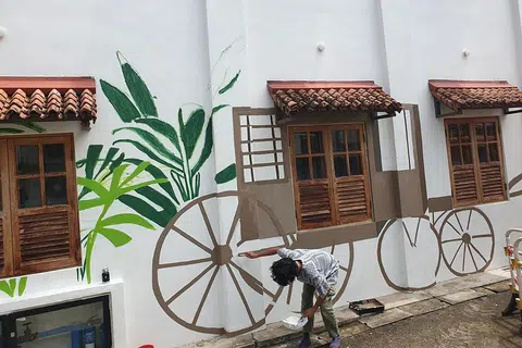 WAJAH BARU: Pelukis mural, Encik Dennis Tan, melukis di permukaan dinding bangunan yang pernah menempatkan Pondok Gelam di 64 Club Street. - Foto BORHAN SAINI