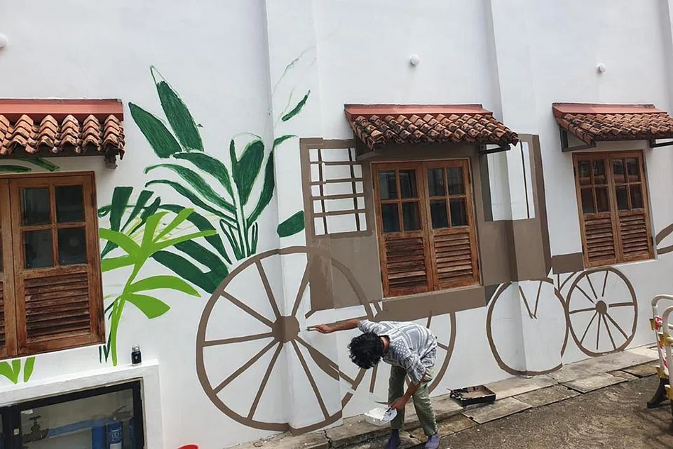 WAJAH BARU: Pelukis mural, Encik Dennis Tan, melukis di permukaan dinding bangunan yang pernah menempatkan Pondok Gelam di 64 Club Street. - Foto BORHAN SAINI