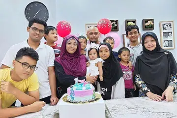 KELUARGA BAHAGIA: Pasangan Cik Tahirah Mohamed (bertudung ungu) dan suaminya Encik Noor Irwan Rashid (tengah, barisan belakang) bersama-sama sembilan anak mereka. Juga tinggal bersama mereka ialah ibu Cik Tahirah, Cik Jawahir Ishak (paling kanan). - Foto ihsan TAHIRAH MOHAMED