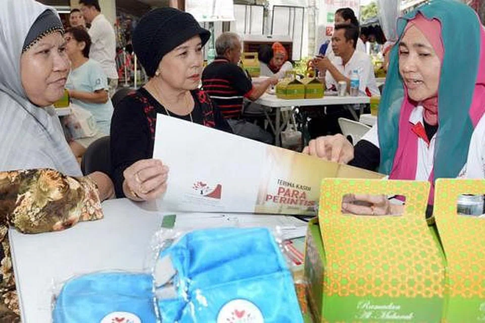 DAPAT PENJELASAN: Cik Ruhani Ismail (tengah), ditemani kawan baiknya Cik Saadiah Abdul Rahim (kiri), dalam sesi perundingan Pakej Generasi Perintis di Joo Chiat Complex. - Foto TAUFIK A. KADER