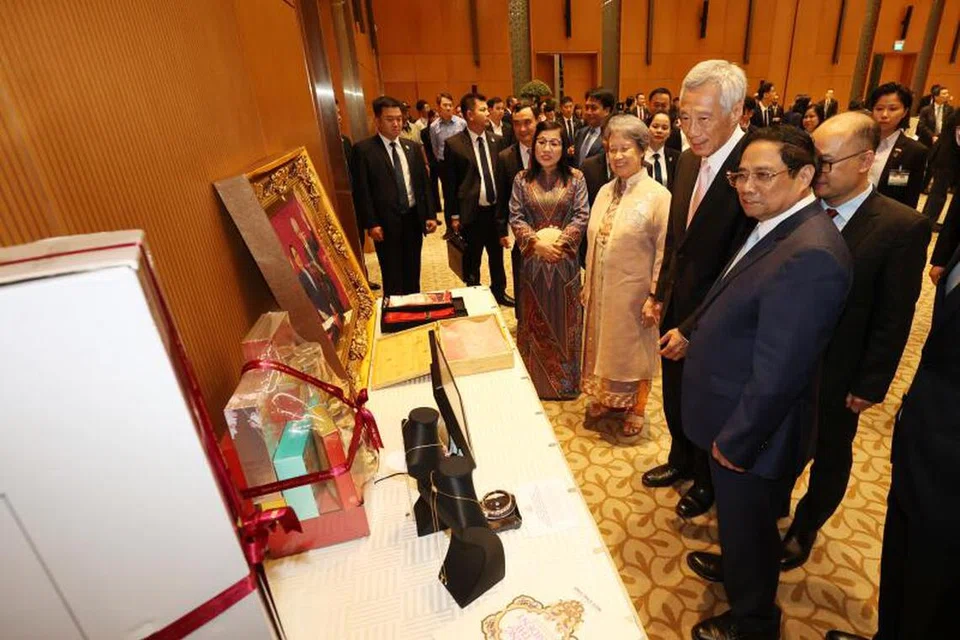 BERTUKAR HADIAH: (Dari kanan) Perdana Menteri Vietnam, Encik Pham Minh Chinh dan Perdana Menteri, Encik Lee Hsien Loong sedang melihat hadiah yang disampaikan oleh kededua pemimpin sebelum majlis jamuan malam rasmi. Turut memerhatikan ialah Cik Ho Ching dan isteri Encik Pham, Cik Le Thi Bich Tran. 