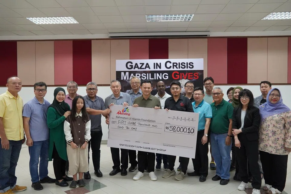 GANDING BAHU: Menteri Negara Kanan (Pertahanan merangkap Tenaga Manusia), Encik Zaqy Mohamad (tengah, baju hijau) bersama penduduk dan wakil daripada kawasan Marsiling menyerahkan cek bernilai $58,000.10 kepada wakil Yayasan Rahmatan Lil Alamin (RLAF), Encik Muhammad Toy-yib Abu Hurairi (tengah, baju hitam).