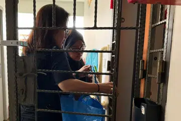 Relawan di M³@Pasir Ris-Punggol, Cik Nurul Atiqah Dzulqarnain, bersama menti dari program #Ampowered, mengagihkan habuan kepada keluarga kurang bernasib baik yang tinggal di blok sewa di Pasir Ris East.