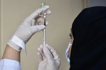 VAKSINASI WAJIB: Seorang pekerja perubatan menyiapkan vaksin Covid-19, AstraZeneca, di pusat vaksinasi sekitar Riyadh. Mulai 1 Ogos, sesiapa yang ingin masuk pejabat atau bangunan kerajaan serta sektor swasta diperlukan menjalani vaksinasi. - Foto AFP/FAYEZ NURELDINE 