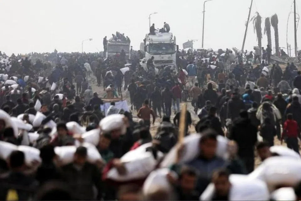 Rakyat Palestin melarikan kampit tepung yang mereka ambil daripada trak bantuan, berhampiran pusat pemeriksaan Israel.