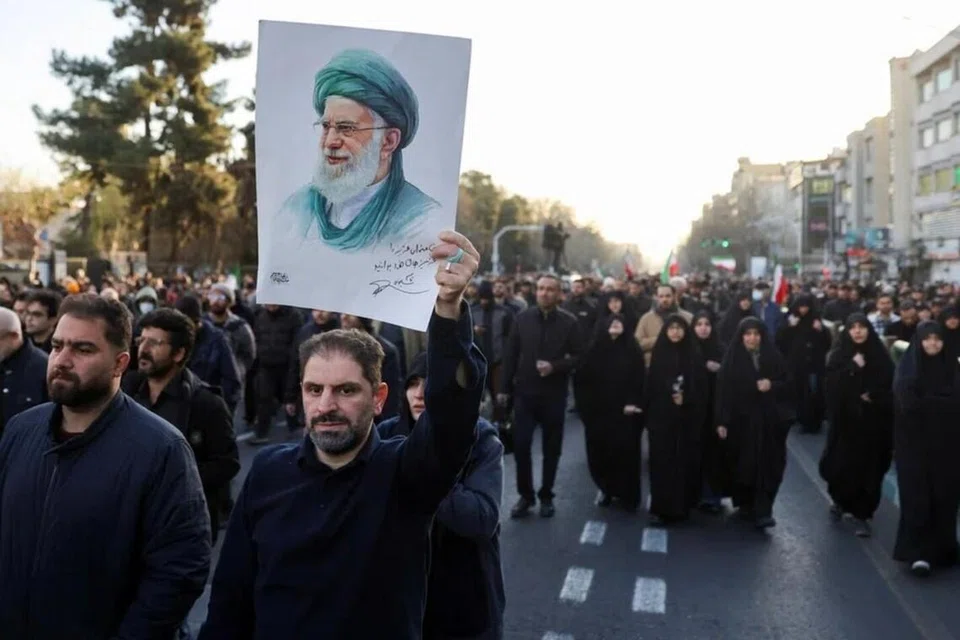 Seorang lelaki mengangkat gambar pemimpin agama tertinggi Iran Ayatollah Ali Khamenei ketika orang ramai berkumpul selepas Khamenei terbunuh dalam serangan Israel dan Amerika Syarikat pada hari Sabtu, di Tehran, Iran, 1 Mac 2026.