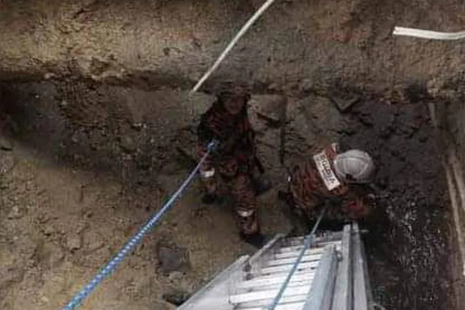Pasukan penyelamat turun ke dalam kawasan lubang benam menggunakan tangga. 