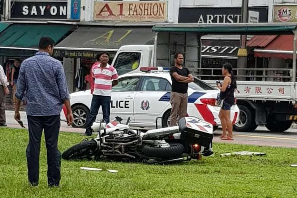 KEMALANGAN JALAN RAYA: Motorsikal yang ditunggang seorang staf sarjan polis trafik terbaring di kawasan berumput di Serangoon Road dalam kejadian pagi tadi (1 Jun 2017). - Foto PEMBACA THE STRAITS TIMES 