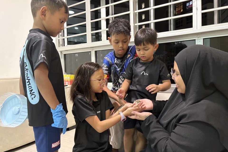 Cik Nurul Fathiah Ramli (kanan) membimbing anak-anaknya dengan cara bagaimana hendak memegang dan membelai hamster.