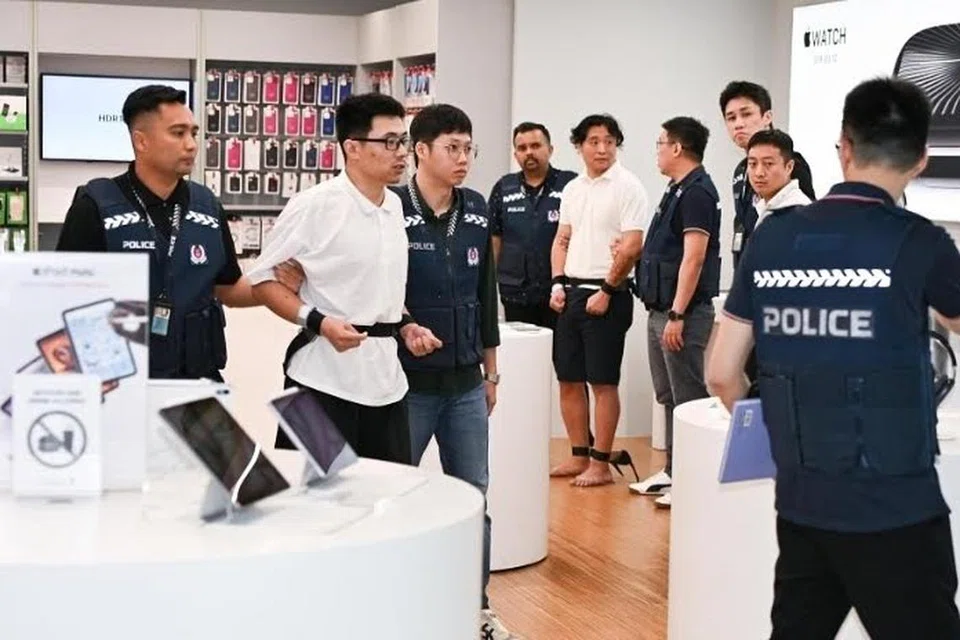 Tertuduh Quek Jian Qing dibawa ke ruang pameran produk Apple di kedai Best Denki di Parkway Parade pada 14 November.