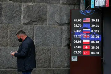 KESAN KORONAVIRUS: Ekonomi dunia akan mengambil masa beberapa tahun sebelum pulih sepenuhnya. Kelihatan seorang lelaki memakai pelitup mengira wang di depan pusat tukaran wang di Kiev, ibu kota Ukraine.
