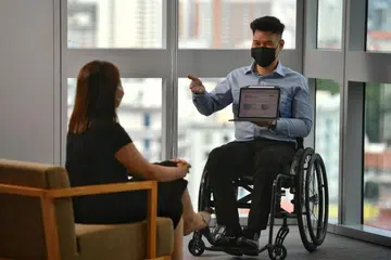 TERUS BERSIKAP POSITIF: Walaupun terpaksa berkerusi roda disebabkan kecederaan teruk pada tulang belakangnya, Encik Asyraf Ghazali berusaha untuk berdikari dengan bekerja sebagai wakil kewangan bersama syarikat insurans Great Eastern. - Foto-foto BH oleh CHONG JUN LIANG