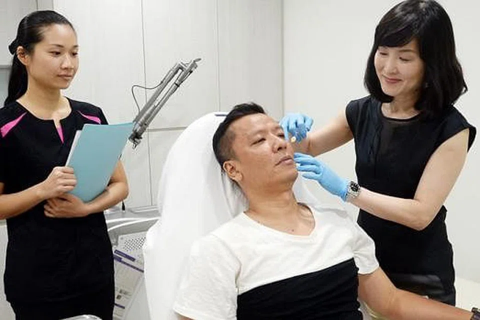 PERBAIKI KULIT: Dr Lam menunjukkan cara beliau menyuntik ubat yang digunakan bagi rawatan wajah Encik Sani bagi memperbaiki kulit mukanya itu. - Foto-foto JOHARI RAHMAT