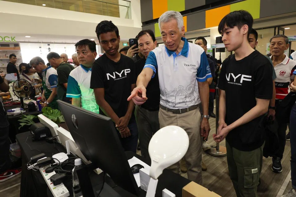 Menteri Kanan, Encik Lee Hsien Loong, berinteraksi dengan dua pelajar Sekolah Kejuruteraan Politeknik Nanyang (NYP), Kopiram Kandeepan, 18 tahun (di kanan Encik Lee), dan Tan Hoe Yang, di acara ‘Eco Fest’ anjuran bersama pertubuhan akar umbi Teck Ghee dan NYP yang berlangsung di Kelab Masyarakat Teck Ghee pada 3 November.