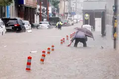 Seorang lelaki meredah jalan yang dinaiki air akibat hujan lebat di Gwangju, Korea Selatan, pada 17 Julai 2025.  