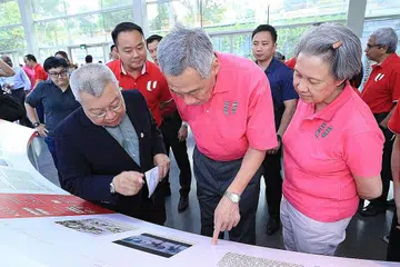 MENGIMBAS KENANGAN LALU: Perdana Menteri, Encik Lee Hsien Loong, dan isteri, Cik Ho Ching, melihat secara dekat gambar-gambar di pameran ReUnion anjuran Kongres Kesatuan Sekerja Kebangsaan (NTUC) di Muzium Negara, kelmarin. - Foto MCI