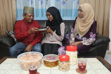 RAYA ISTIMEWA: Cik Yusrina (tengah) bersama ibu dan bapanya, Cik Rosnani Ismail dan Encik Ya'akob Jani. Hari Raya tahun ini lebih istimewa kerana kejayaan Cik Yusrina mencapai puncak Gunung Everest serta kehadiran cucu pertama Encik Ya'akob dan Cik Rosnani. - Foto-foto QASHRUL HIDAFI, ihsan NUR YUSRINA YA'AKOB 