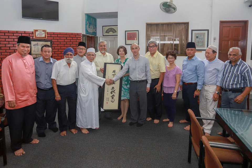 TANDA HUBUNGAN AKRAB: Imam Masjid Ba'alwie Habib Hassan Al-Attas (lima dari kiri) berjabat tangan dengan Encik Chua Tian Siong, Presiden Persatuan Amitabha Singapura. Persatuan agama Buddha itu mendermakan 20 tan beras kepada masjid sempena Ramadan tahun ini. - Foto BH oleh IQBAL FAIZAL