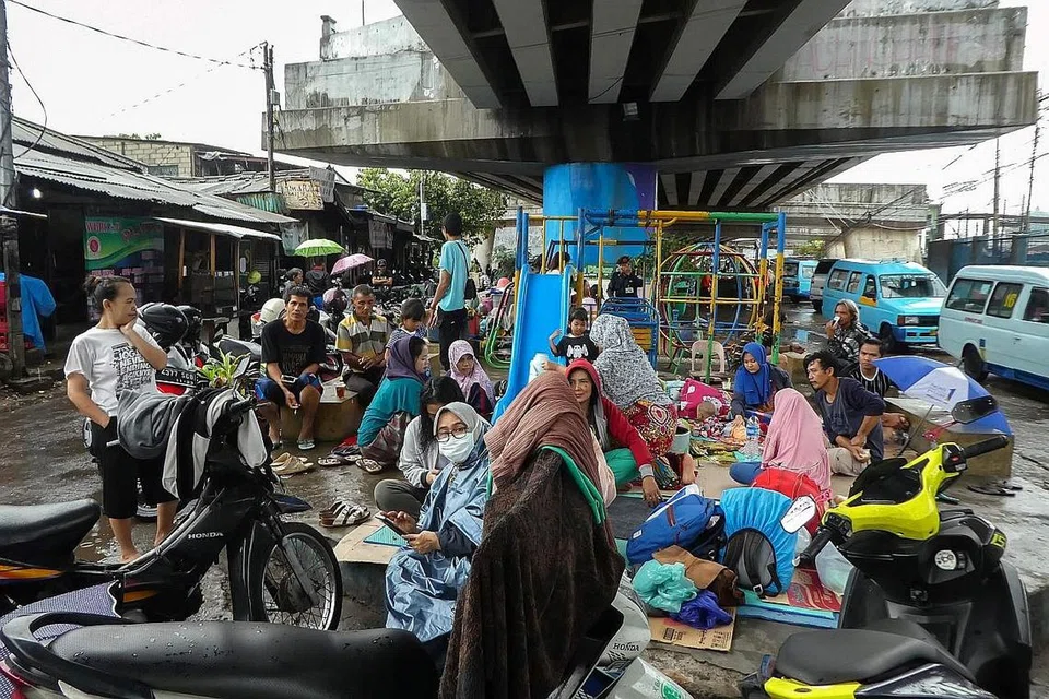 CARI PERLINDUNGAN: Orang ramai mencari perlindungan di bawah sebuah jejambat apabila hujan semalaman mengakibatkan banjir di beberapa kawasan di Jakarta pada Tahun Baru. - Foto AFP