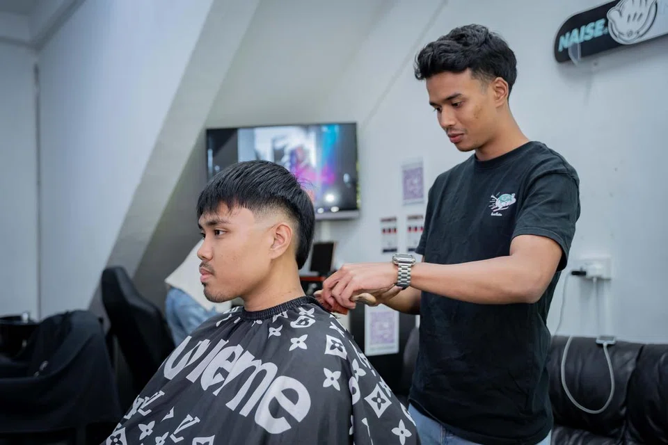 Encik Izz Danish Muhammad Razali (kanan) telah ke Malaysia dan Indonesia untuk meningkatkan kemahiran dengan mempelajari daripada pelbagai tukang gunting rambut yang berpengalaman di sana.