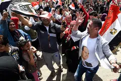 SOKONGAN MELUAS: Rakyat Mesir menari, dengan membawa bendera negara dan memakai kemeja-T tertera gambar Presiden Abdel Fattah al-Sisi, di luar sebuah pusat mengundi di al-Omraniya di Giza semasa pilihan raya pada 26 Mac. Encik Fattah popular dalam kalangan rakyatnya. - Foto AFP