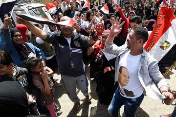 SOKONGAN MELUAS: Rakyat Mesir menari, dengan membawa bendera negara dan memakai kemeja-T tertera gambar Presiden Abdel Fattah al-Sisi, di luar sebuah pusat mengundi di al-Omraniya di Giza semasa pilihan raya pada 26 Mac. Encik Fattah popular dalam kalangan rakyatnya. - Foto AFP