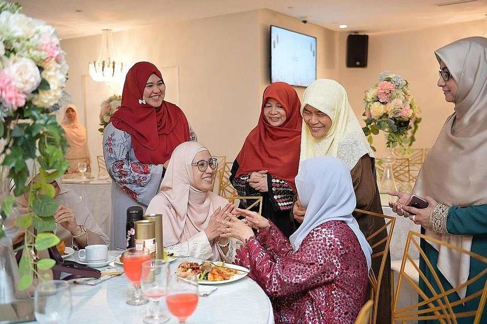 JUNJUNG SUMBANGAN: Naib Presiden Persatuan Ulama dan Guru-Guru Agama Islam Singapura (Pergas), Ustazah Sukarti Asmoin (berhijab kuning), sedang beramah mesra dengan keluarga penyumbang semasa majlis perjumpaan Hari Raya anjuran persatuan itu di Iris City Plaza, dalam usahanya memberi penghormatan kepada sumbangan sukarelawan dan penyumbang. - Foto BH oleh SHINTARO TAY CH