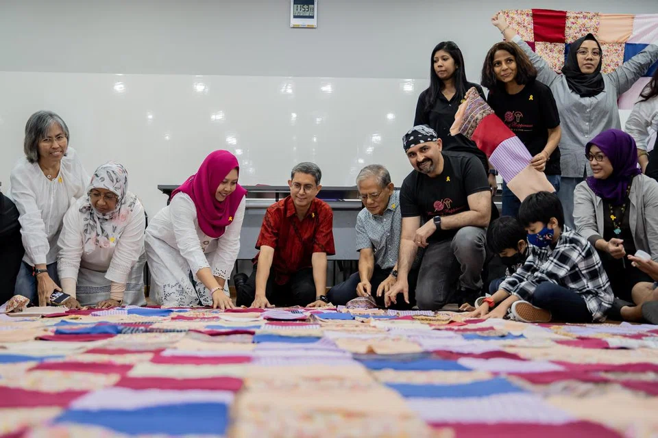ATUR HASIL TANGAN: Menteri Negara (Ehwal Dalam Negeri merangkap Pembangunan Negara), Profesor Madya Muhammad Faishal Ibrahim (empat dari kiri), dan Setiausaha kehormat Dana Pendidikan Harun Ghani (HGEF), Cik Haslinda Putri Harun (tiga dari kiri), menyusun jahitan kuilt yang dihasilkan peserta dalam satu majlis tahunan HGEF pada 23 Disember.