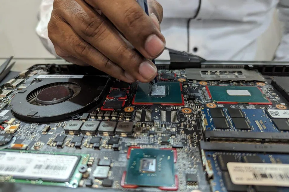 Seorang teknisyen kelihatan menyapu cecair lapisan haba baru di atas cip komputer riba bagi memastikan suhu cip itu dapat dikawal dengan baik.