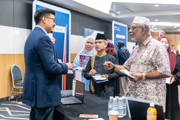 Encik Imran Rahim (kiri), peguam dan ahli Kumpulan Kerja Perancangan Legasi Islam, berkongsi maklumat mengenai instrumen wasiat, hibah dan faraid bersama pengunjung di Perkampungan Legasi Islam pada 2024.