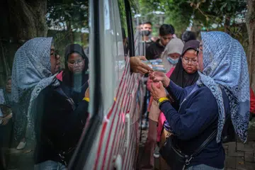 Orang ramai beratur untuk menukar wang kepada denominasi kecil di sebuah pengurup wang bergerak di Palembang, Sumatera Selatan, pada 4 Mac 2026, menjelang sambutan Aidilfitri apabila orang ramai secara tradisi mengagihkan wang kepada saudara-mara yang berkunjung. 