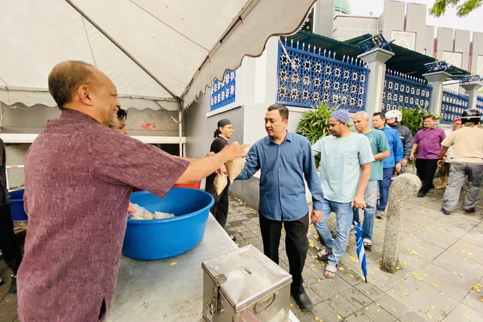 Pengerusi Masjid Jamek Kampung Baru, Kuala Lumpur, Datuk Mohd Khay Ibrahim (kiri), membantu pasukan sukarelawan mengagihkan bubur lambuk percuma kepada orang ramai selepas solat Asar berjemaah di masjid berkenaan.