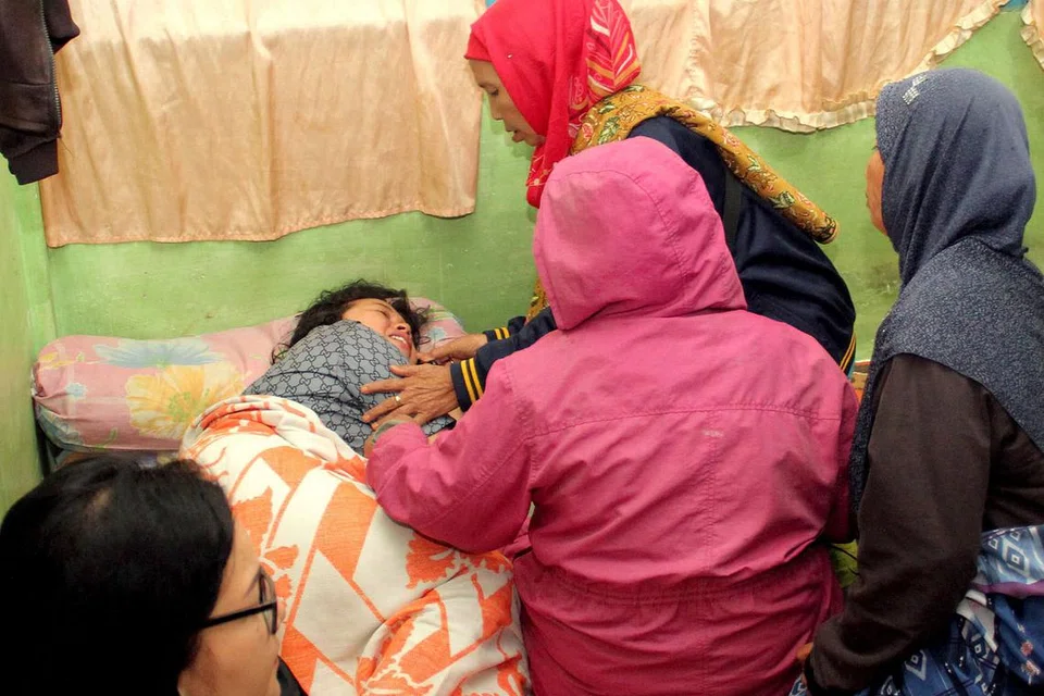 SELAMAT: Seorang mangsa yang terselamat (gambar atas) dikelilingi anggota keluarganya selepas feri yang dinaiki terbalik di Danau Toba kelmarin. Sekurang-kurangnya seorang penumpang meninggal dunia sementara ramai yang lain masih hilang selepas feri yang membawa sekitar 80 orang terbalik dan tenggelam. - Foto AFP