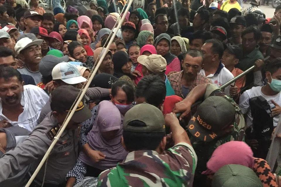 PEGAWAI PEMERINTAH BANYAK MEMBANTU: Selain polis, anggota tentera turut membantu mengawal keamanan ketika penduduk desa di Probolinggo, Jawa Timur, bersesak-sesak mahu mengambil sekilogram daging sempena upacara korban tahun ini. - Foto DARUL AJYAL & SERVICES