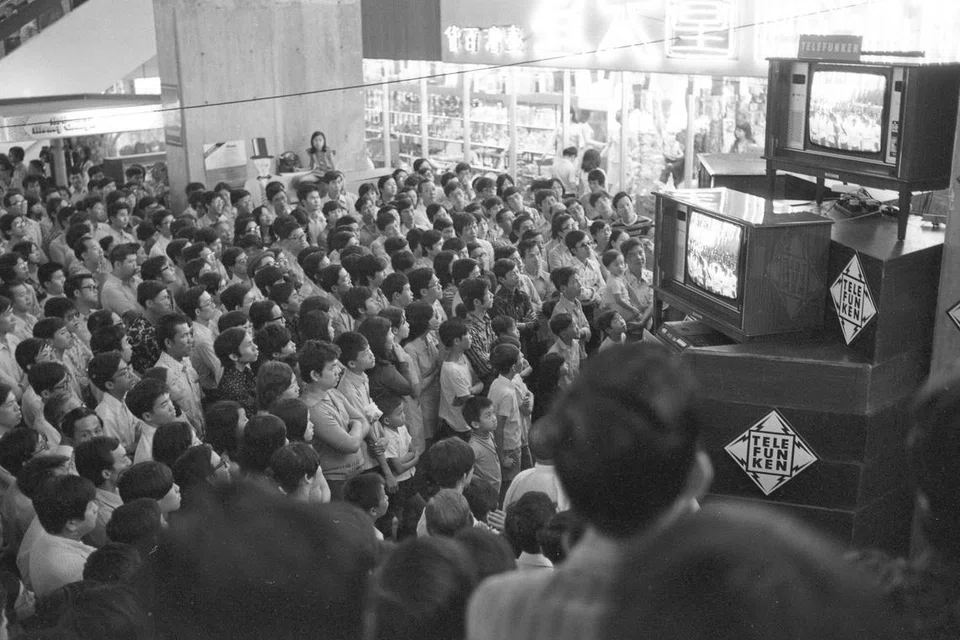 Penonton buat kali pertama menyaksikan siaran langsung Perbarisan Hari Kebangsaan (NDP) 1974 secara berwarna di televisyen. Gambar menunjukkan keadaan di People’s Park Complex ketika itu. 