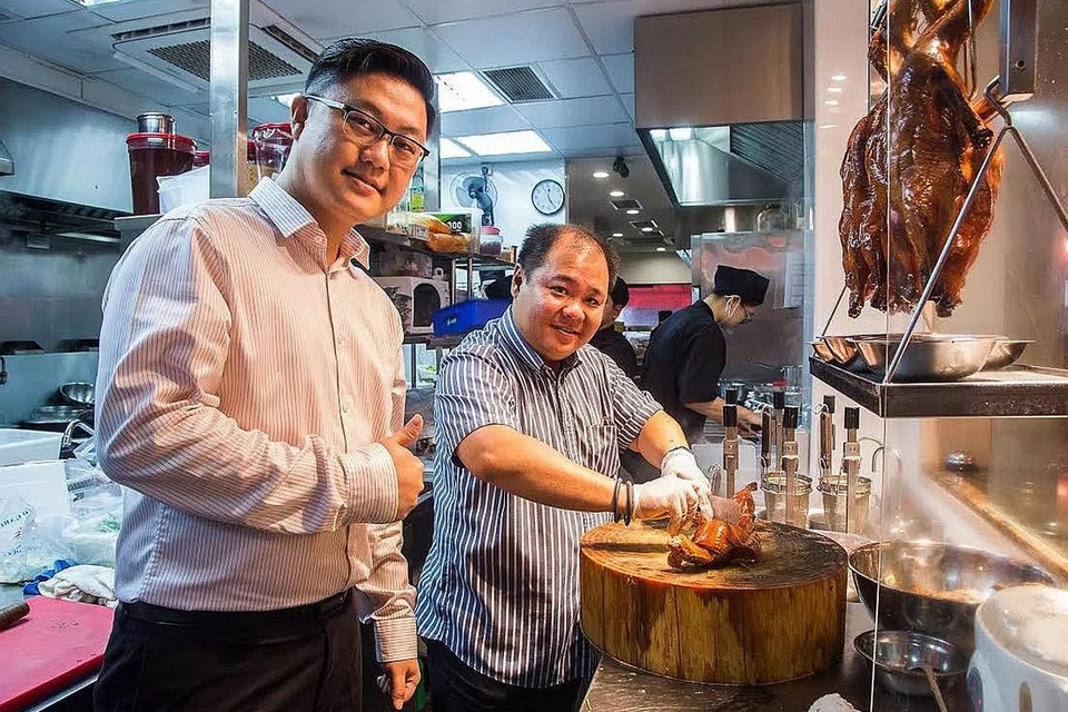 'BUKA' SUASANA: Bahagian dapur The Dim Sum Place menawarkan suasana terbuka bagi para pelanggan melihat sendiri sajian yang disediakan termasuk hidangan yang menggunakan daging itik seperti yang ditunjukkan Encik Guan (kiri) dan Encik Low. - Foto ZALEHA ABDUL KADER