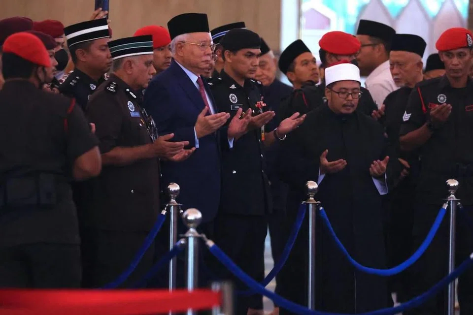 Pegawai Polis Diraja Malaysia mengiringi mantan Perdana Menteri Malaysia, Encik Najib Tun Razak (tengah), yang sedang menjalani hukuman penjara, untuk memberi penghormatan terakhir pada 15 April.