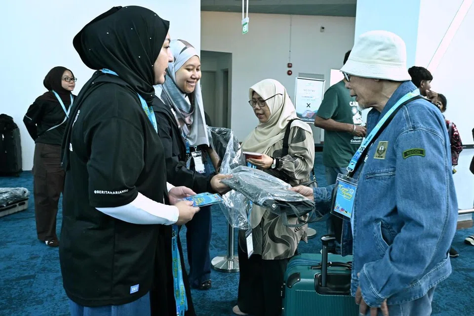 Peserta menerima lanyard serta beg galas ketika mendaftar masuk kapal persiaran.