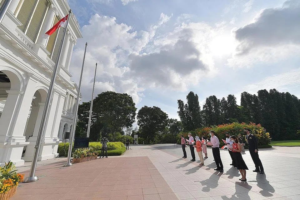 MENAIKKAN BENDERA: Presiden Halimah Yacob dan PM Lee Hsien Loong (tiga dan dua dari kiri) bersama beberapa pegawai daripada pejabat mereka berdiri penuh hormat di upacara menaikkan bendera Singapura. - Foto BH oleh ALPHONSUS CHERN