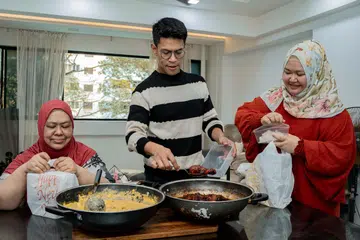 Perniagaan dari rumah (HBB), Dapur Mother Mary, yang bermula pada 2018, menyediakan hidangan mangkuk tingkat sempena Ramadan sejak 2021. Ia kini bekerjasama dengan jenama seperti Santan by Auntie Bedah, Salaam Cola, dan Jongkong Cik Enon. (Dari kiri) Cik Mariam Zakariya bersama anak-anaknya, Encik Tajjlee Rahim dan Cik Sriwayuni Rahim, dengan lauk nangka lemak daging dan ayam masak kicap.