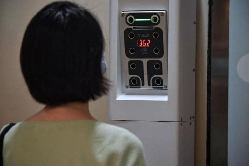 Seorang pengguna berdiri di depan kios periksa suhu di stesen MRT Braddell. 