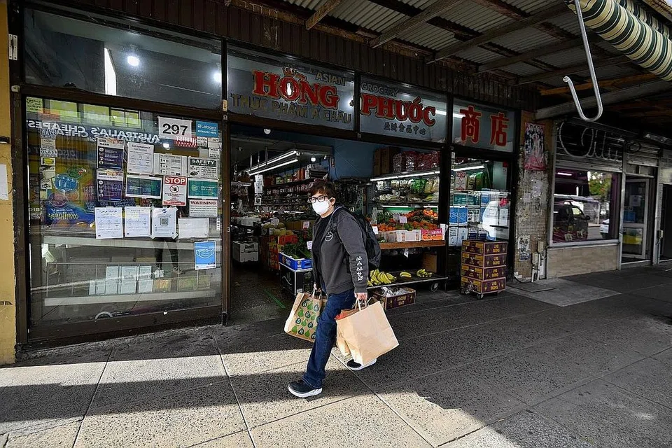 KEADAAN LENGANG: Seorang lelaki berpelitup dilihat membawa barangan yang dibeli melepasi barisan kedai di Marrickville, Sydney, New South Wales, Australia, semalam. - Foto EPA-EFE