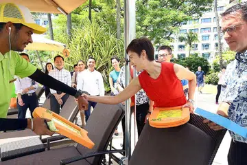 MUDAHKAN TUGAS: Cik Josephine Teo sedang meninjau jam yang dipakai pekerja pelayan di bar kolam renang Shangri-La Rasa Sentosa, sebagai sebahagian daripada Alat Isyarat Bar Kolam Renang, bagi memudahkan pekerja melayan tetamu hotel. - Foto ZAOBAO